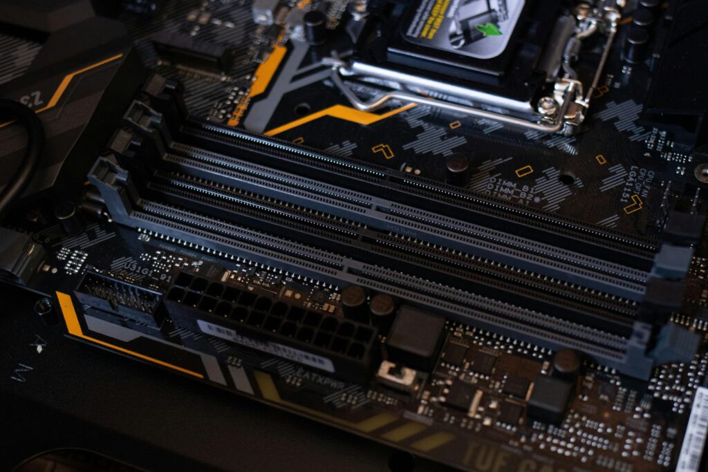 pexels-photo-2582932-2582932-1 Detailed view of a computer motherboard showcasing RAM slots and electronic components.